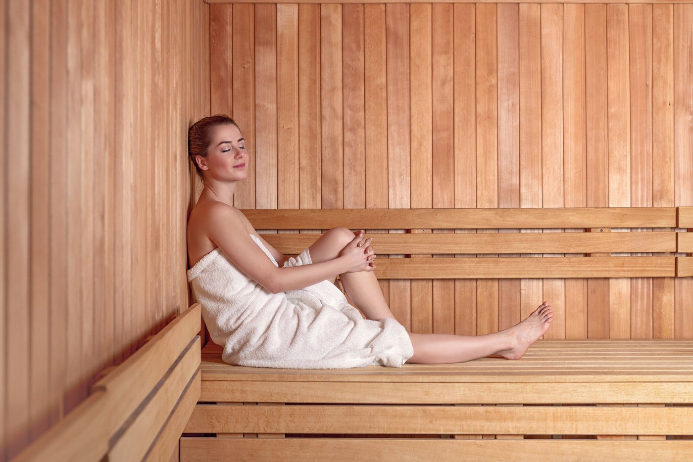 A women relaxing with her eyes closed inside a sauna