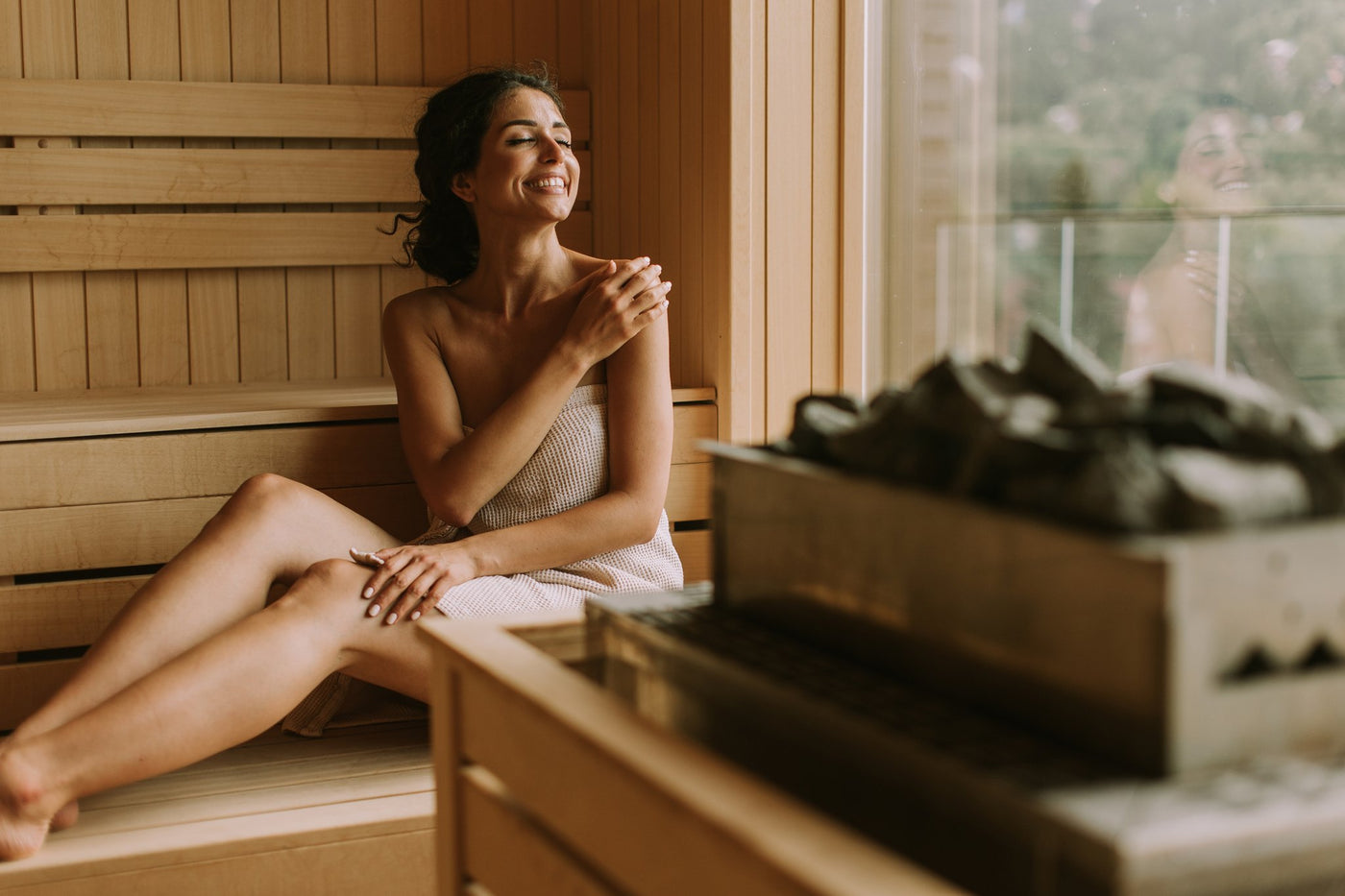 A women smiling with joy inside a sauna whilst looking out the window